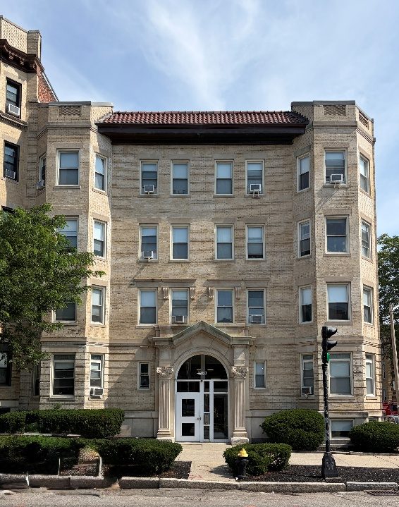 A symmetrical Allston apartment building with a central arched entrance